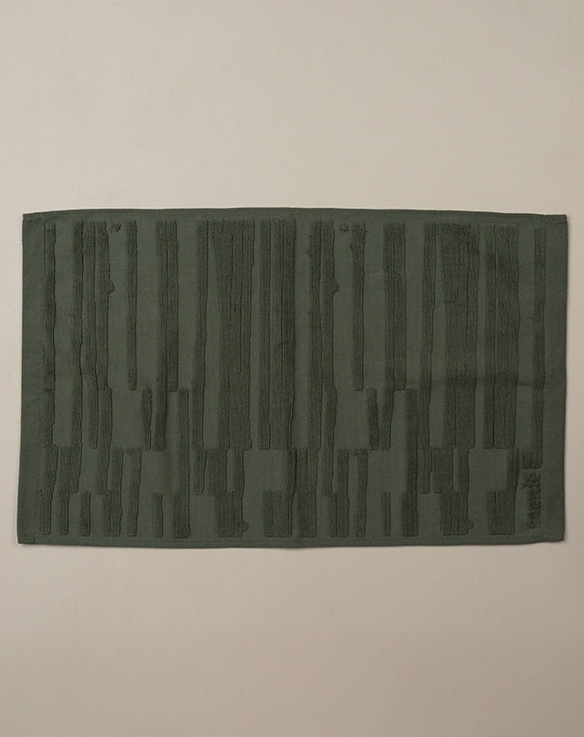Dark green textured rug on a beige background
