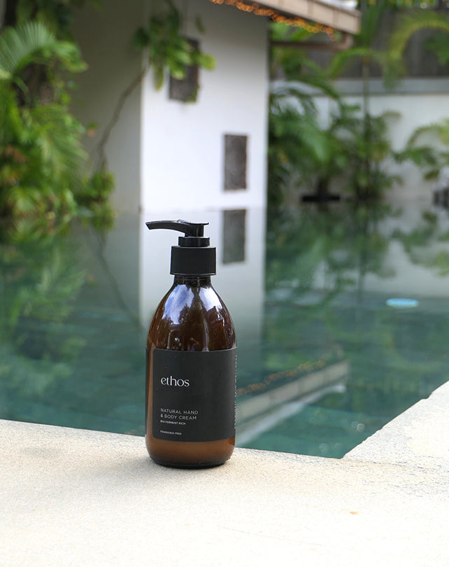 Bottle of ethos body wash on a ledge with a pool and greenery in the background
