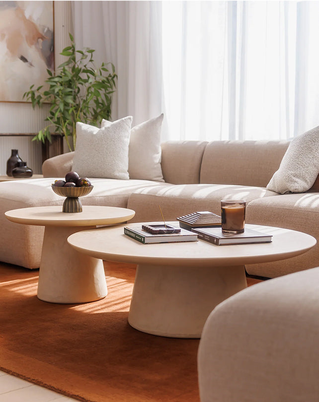 Modern living room with beige sofa, coffee table, and decorative items.