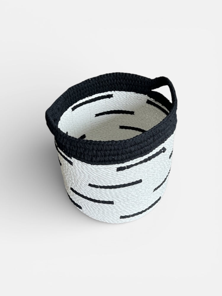 Woven basket with black handle on a white background
