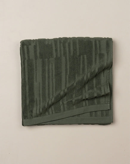 Folded green towel on a beige background