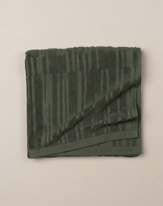 Folded green towel on a beige background