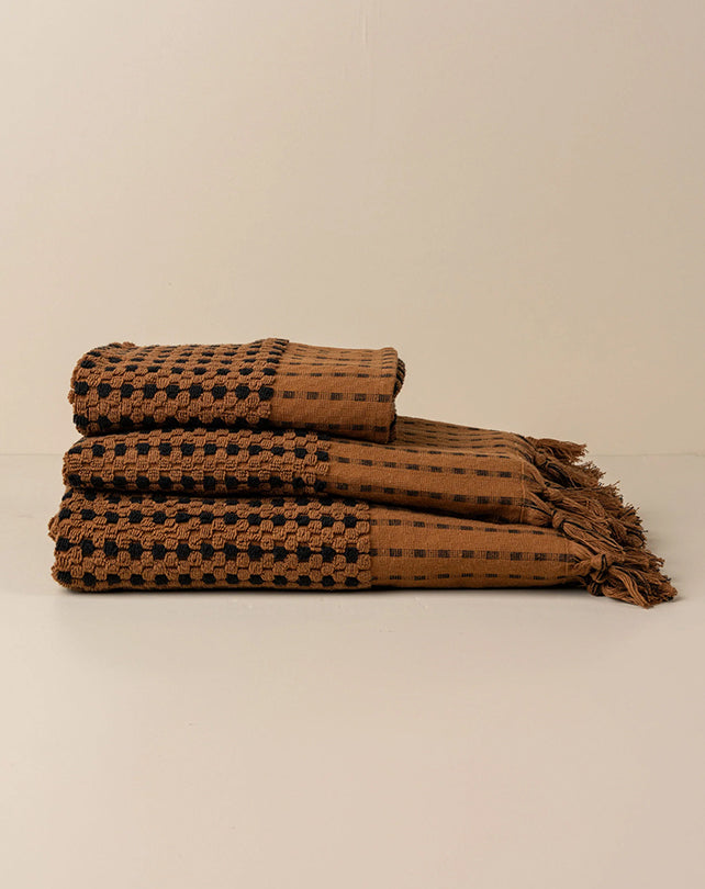 Brown woven blanket with black pattern on a beige background