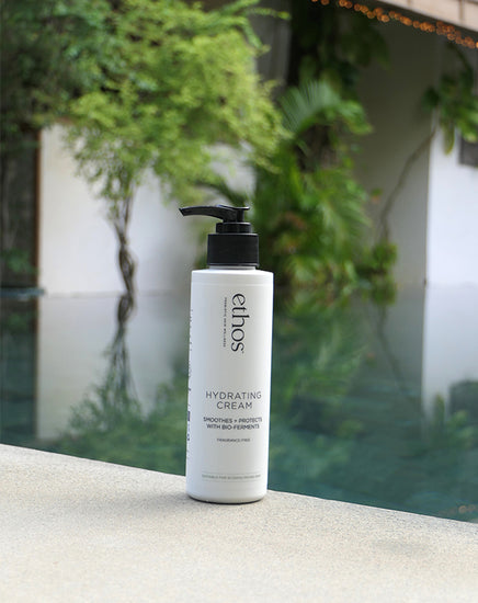 Ethos hydrating cream bottle on a ledge with greenery in the background