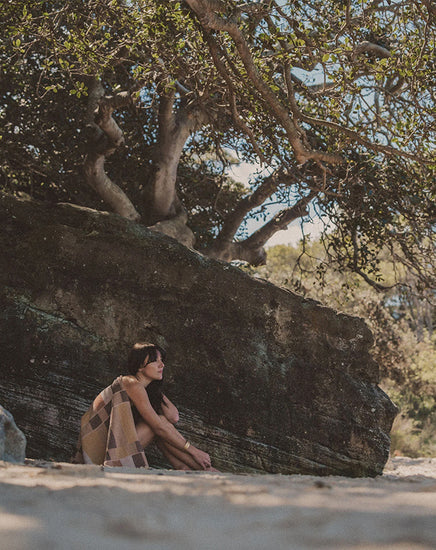 Person sitting under a large tree with a rocky outcrop