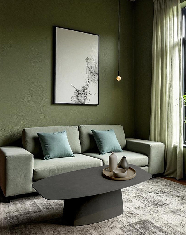 Modern living room with a gray sofa, coffee table, and abstract art on a green wall.