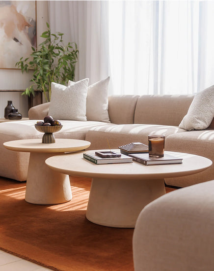 Modern living room with beige sofa, coffee table, and decorative items.