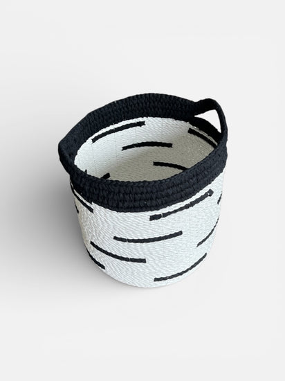Woven basket with black handle on a white background