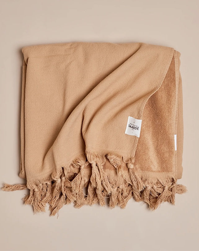 Beige towel with tassels on a beige background