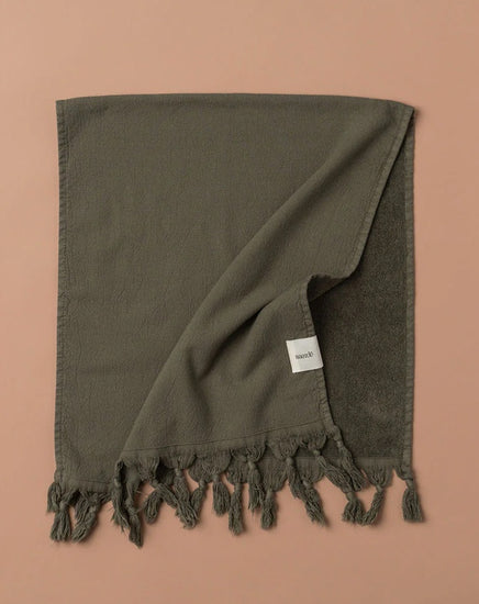 Dark green towel with tassels on a brown background
