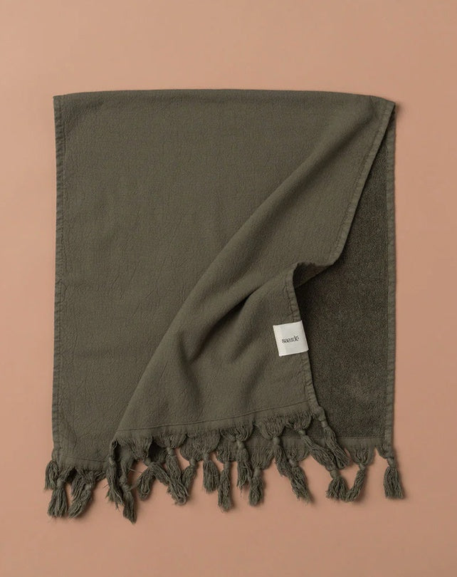 Dark green towel with tassels on a brown background